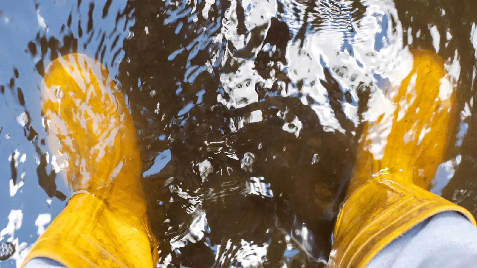 Safety boots standing in shallow water during cleanup operation