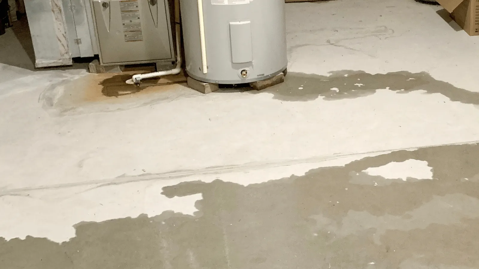 Water pool surrounding the base of a water heater on a concrete floor
